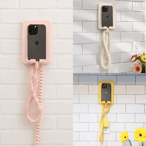 Three views of a wall-mounted phone adapter showing a smartphone connected to a coiled cord phone receiver. The adapter is shown in pink, cream, and yellow, mounted on white brick and subway tile walls.
